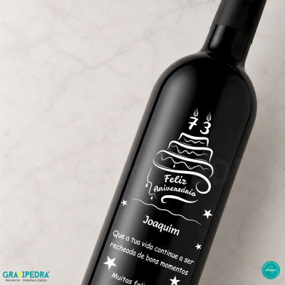 Garrafa de vinho preta com rótulo de aniversário personalizado branco num fundo claro