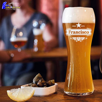 Copo alto com cerveja clara e espuma, etiqueta Francisco, prato com amendoins e limão, mesa de madeira.