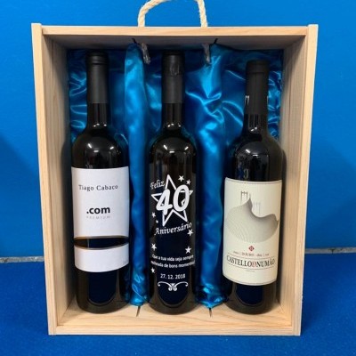Três garrafas de vinho em caixa de madeira com forro azul