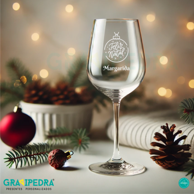 Copo de vidro com texto decorativo de Natal cercado por decorações natalinas.