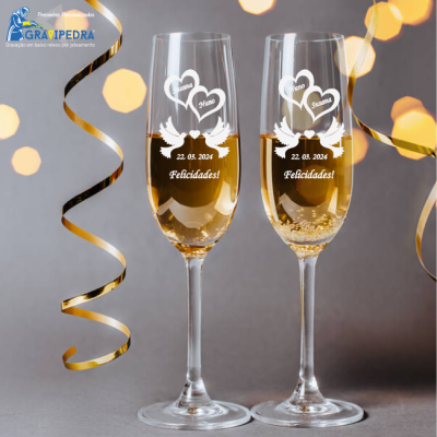 Duas taças de champanhe com gravações personalizadas e fitas douradas ao fundo