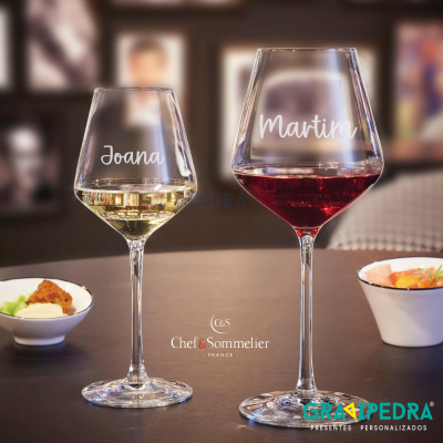 Dois copos de vinho personalizados com nomes, fundo de bar ou restaurante.