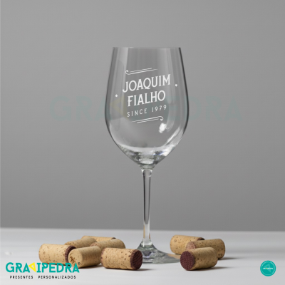 Taça de vinho transparente com texto branco, rodeada por rolhas de cortiça.