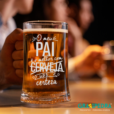Copo de cerveja com texto impresso segurado por uma mão num ambiente interno