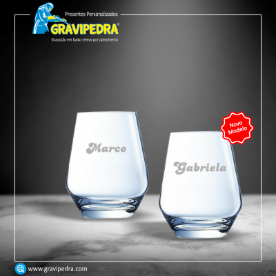 Dois copos gravados com nomes Marco e Gabriela, sobre superfície cinzenta.