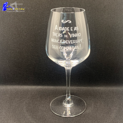 Copo de vinho em vidro com texto gravado sobre fundo preto