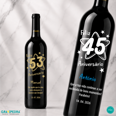 Garrafas de vinho tinto personalizadas com rótulos de aniversário em preto, dourado, branco e azul sobre mesa de mármore.
