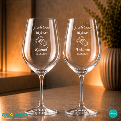Duas taças de vinho com gravação para celebração de 50 anos em fundo quente.