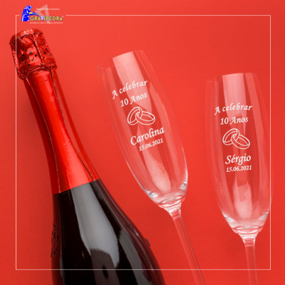 Garrafa de champanhe preta com tampa vermelha e duas taças de champanhe personalizadas com texto em fundo vermelho