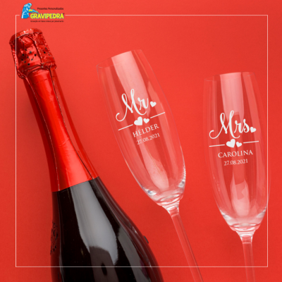 Garrafa de champanhe e duas taças gravadas personalizadas sobre fundo vermelho