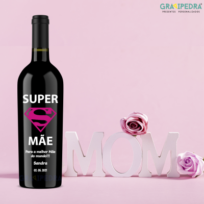 Garrafa de vinho personalizada com texto para mãe ao lado de letras MOM e flores em fundo rosa