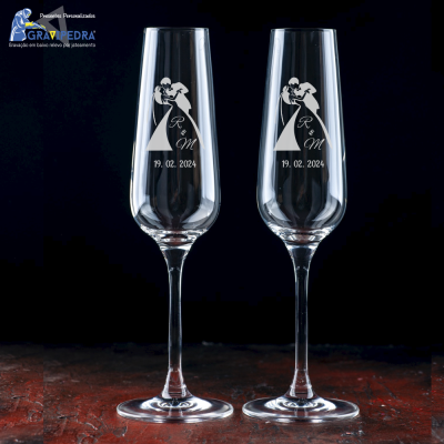 Dois copos de champanhe com gravações brancas de casal, iniciais e data.