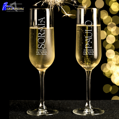 Dois copos de champanhe com nomes e data gravados, cenário festivo