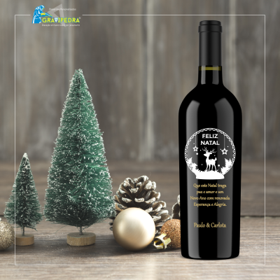 Garrafa de vinho natalícia com decoração de árvores e bolas de Natal sobre mesa de madeira