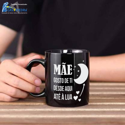 Caneca preta com texto branco e ilustrações, mão segurando