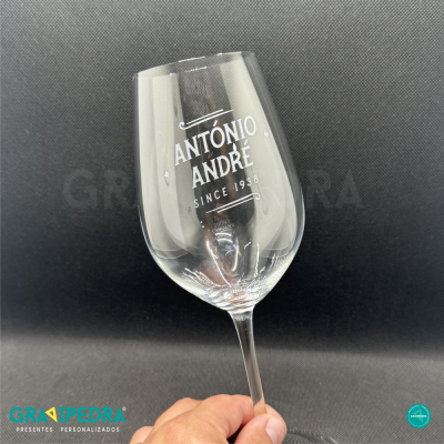 Copo de vinho transparente com texto Antonio André e fundo cinza