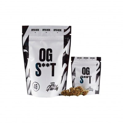 Duas embalagens brancas e pretas com texto OG S**T e erva seca ao lado