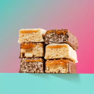 Barras energéticas cortadas com recheio de caramelo e cobertura de chocolate em fundo colorido