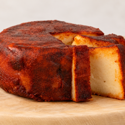 Queijo curado com crosta vermelha apimentada cortado em fatias num suporte de madeira