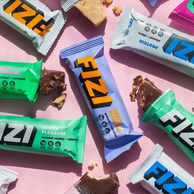 Barritas energéticas em várias embalagens coloridas sobre fundo rosa.