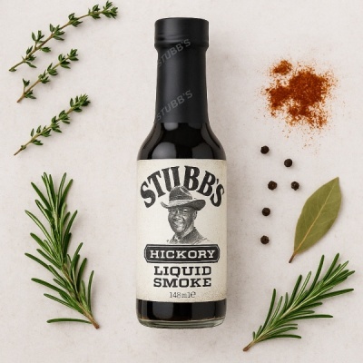 Frasco de molho de fumado líquido rodeado por ervas e especiarias