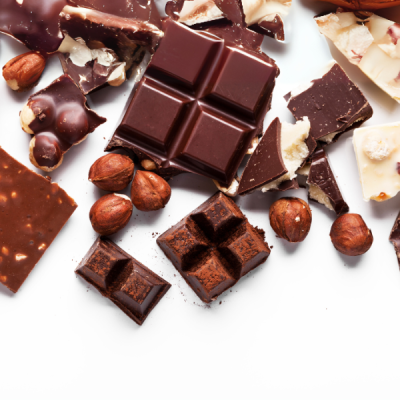 Pedaços variados de chocolate escuro e branco com avelãs sobre fundo branco