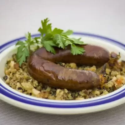 Prato com enchido assado sobre migas e rama de salsa.