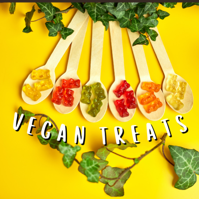 Colheres de madeira com gomas em forma de ursinhos coloridos sobre fundo amarelo com folhas de hera e texto VEGAN TREATS.