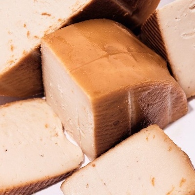 Fatias e bloco de queijo bege com crosta castanha