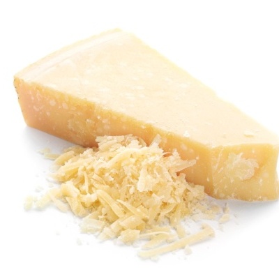 Bloco triangular de queijo duro amarelo com queijo ralado à frente em fundo branco.