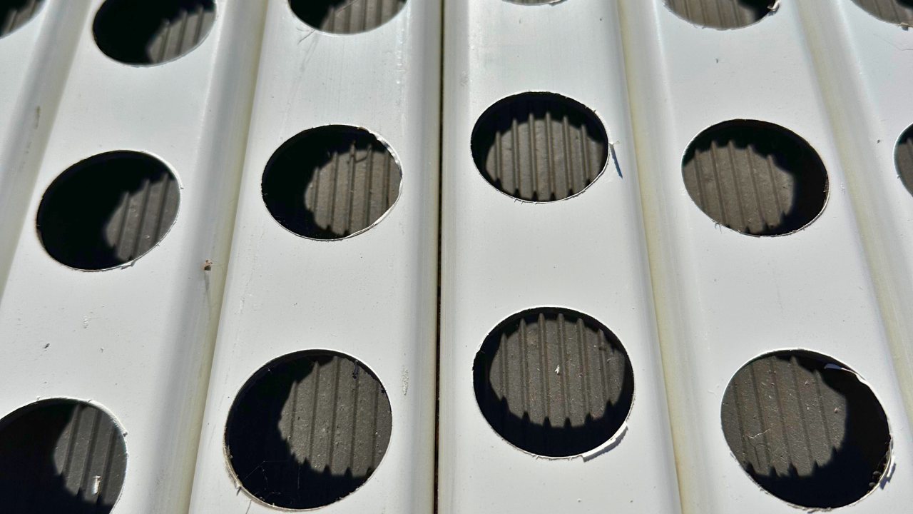 Superfície metálica branca com buracos circulares e textura preta no fundo