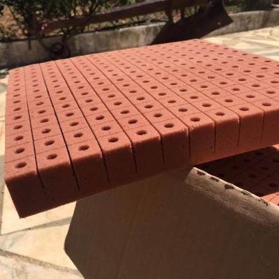 Tablero Espuma Fenólica 2x2x2.4 Falsete de espuma cor tijolo com orifícios circulares e caixa de cartão em ambiente exterior