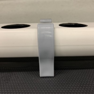 Suporte cinzento em estrutura tubular branca com aberturas pretas