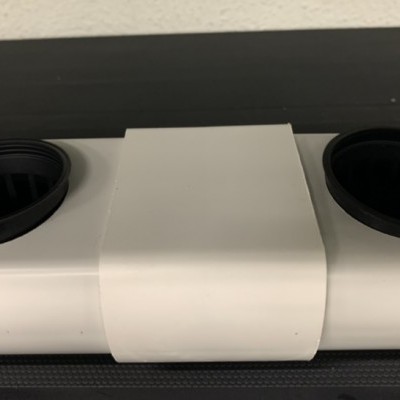 Suporte cilíndrico branco com aberturas circulares pretas em superfície escura