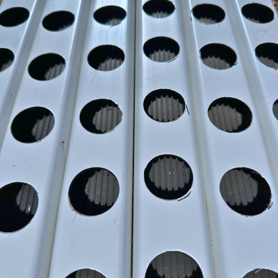 Superfície branca com aberturas circulares alinhadas que mostram textura preta por baixo