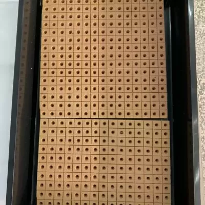 placas bege com pequenos furos em bandeja preta