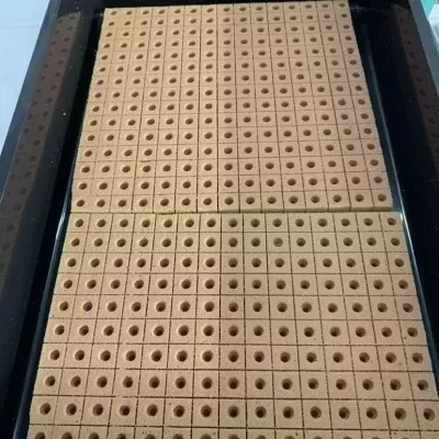 Placa preta com grelha de cubos castanhos claros com buracos