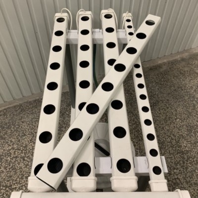 Estrutura branca com tubos perfurados pretos dispostos em leque