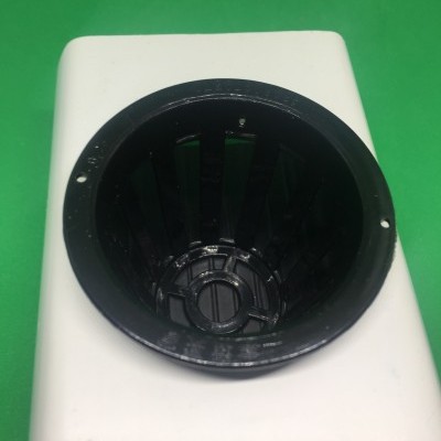 Dispositivo branco com abertura circular preta sobre fundo verde