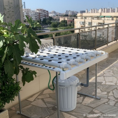 Sistema hidropónico con tubos blancos y cubeta en terraza