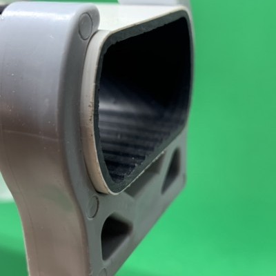 Produto plástico cinza claro com interior preto texturizado sobre fundo verde