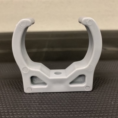 Suporte plástico branco em forma de U com base retangular sobre superfície preta texturada.