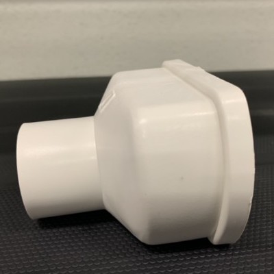 Conector branco de tubo em plástico sobre superfície preta