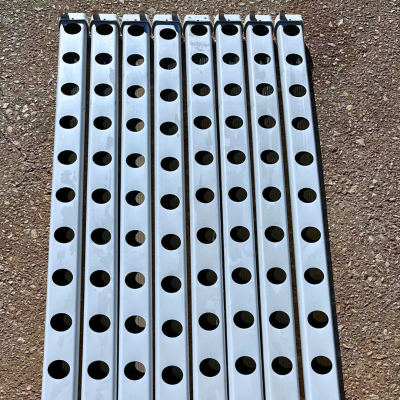 Barras metálicas prateadas com furos circulares alinhadas no chão