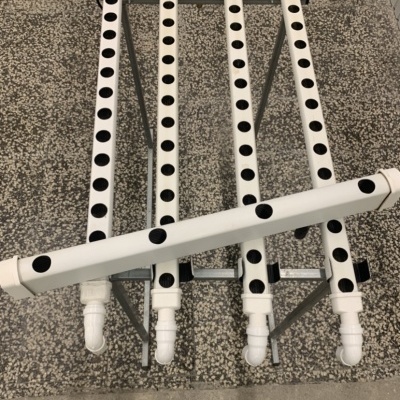 tubos de PVC brancos com furos pretos para cultivo hidropónico sobre estrutura metálica