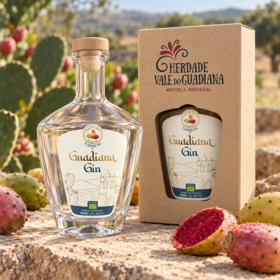 Garrafa de gin Guadiana com embalagem ao lado, rodeada por figos da índia sobre pedra