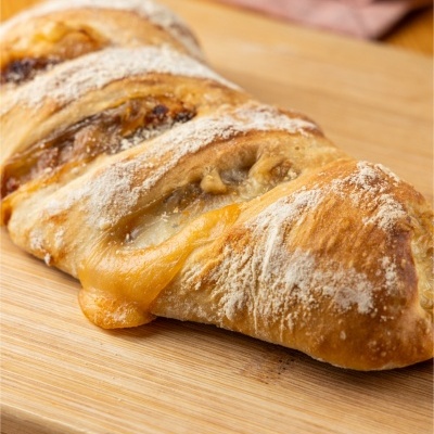 Pão rústico com queijo derretido sobre tábua de madeira