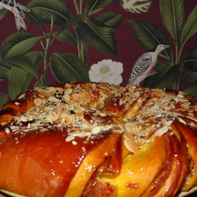 Doce entrançado dourado com amêndoas, fundo de folhas e pássaros