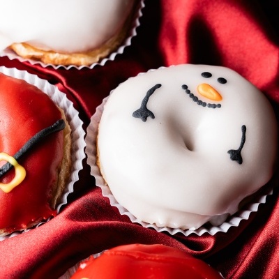 Donuts natalícios decorados com glacê branco e vermelho sobre tecido vermelho
