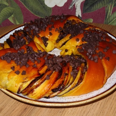 Doce em forma de coroa com pepitas de chocolate num prato branco com borda castanha